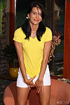 A girl posing in yellow T-shirt and white skirt.